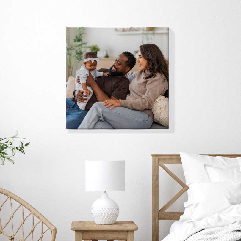 400x400mm stretched canvas print with family photo of mother, father, and daughter sitting on couch smiling together