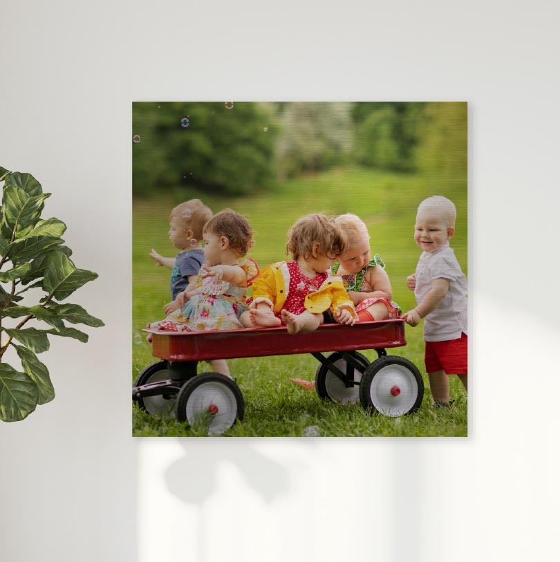 600x600mm brushed silver aluminium print with photo of children playing on toy wagon outdoors