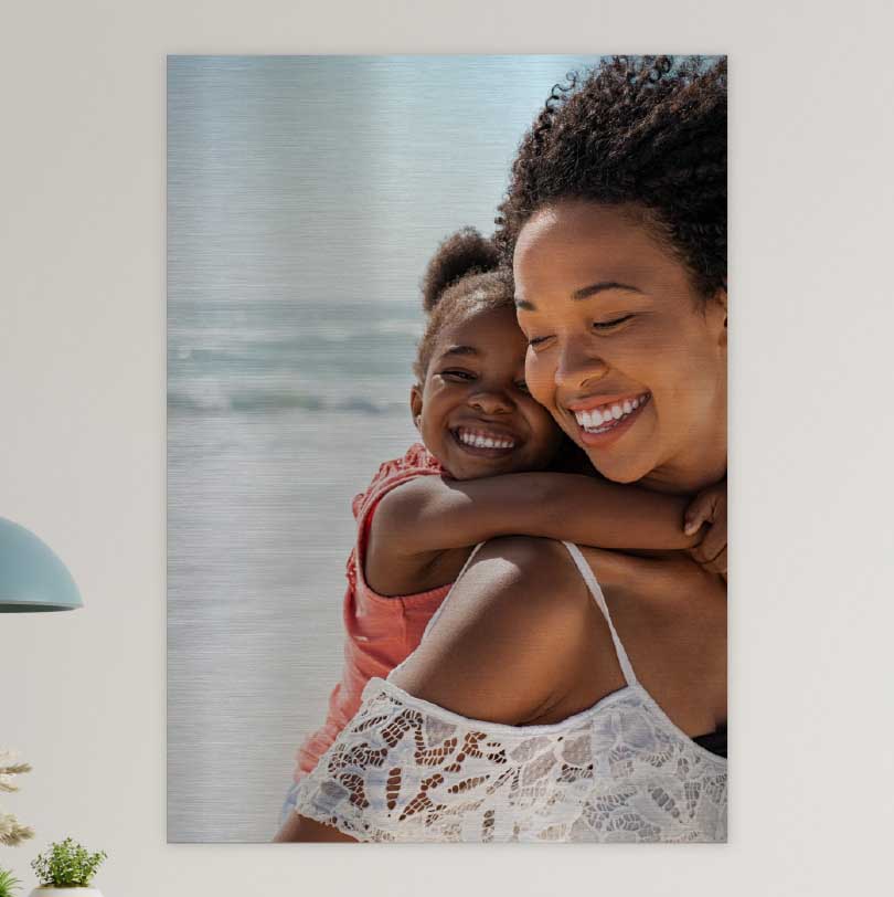 900x600mm brushed silver aluminium print with photo of mother walking on beach carrying child on her back