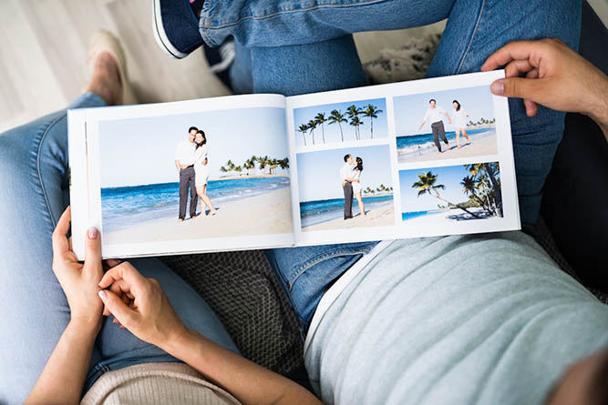 Couple Looking at Family Landscape Photobook Couple sitting together looking through a landscape family photobook filled with printed photo memories.