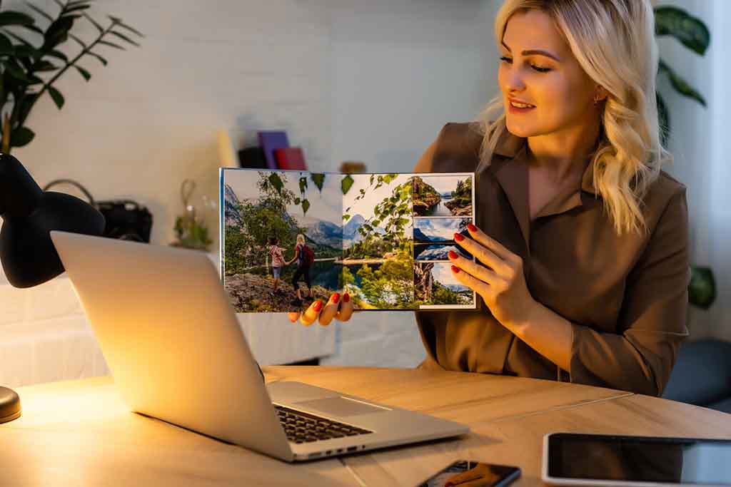 Woman designing a personalised photobook on a laptop with online photo editor software